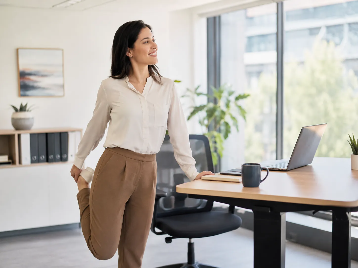 Een professional neemt een korte stretchpauze naast haar bureau tijdens een drukke werkdag.